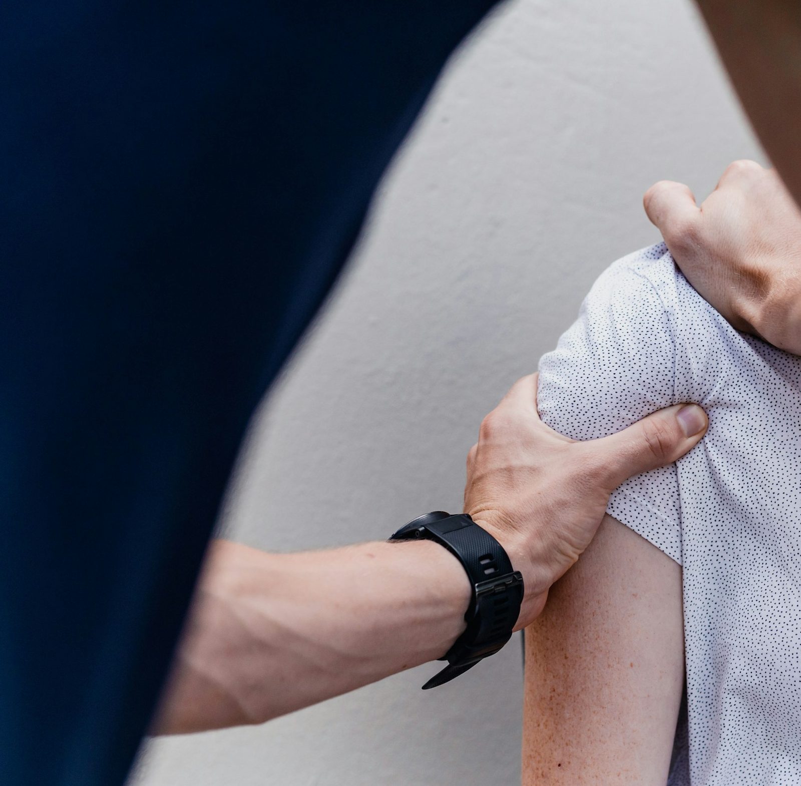 A practitioner's hands on a patient's shoulder during an assessment