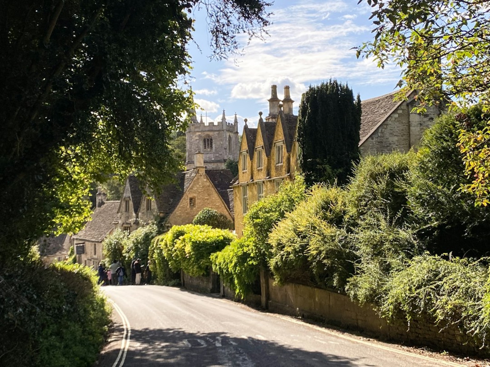 A quiet tree-lined village lane with stone houses